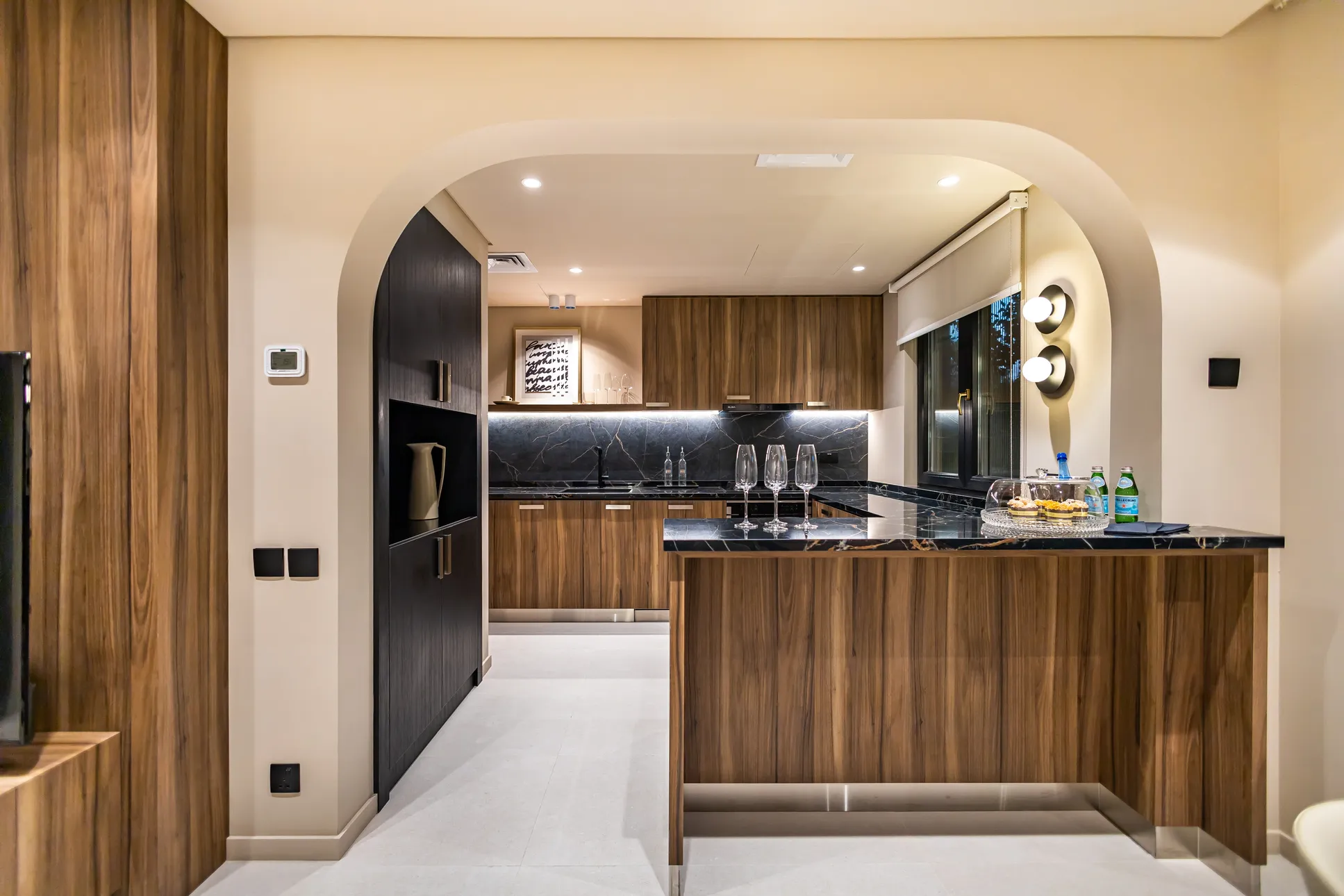 Modern kitchen interior in Springs 9 townhouse, featuring wood cabinetry, marble countertops, and sleek design elements in a luxurious Qatar Property.